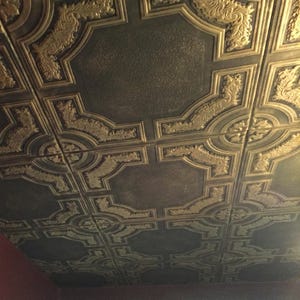 May include: A ceiling covered in decorative ceiling tiles with a gold and brown pattern.