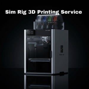 Pode incluir: Uma impressora 3D cinza com um recipiente de filamento transparente no topo, contendo bobinas de filamento azul, verde e vermelho. O texto "Sim Rig 3D Printing Service" está no topo.