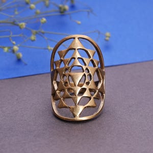 Anillo con diseño de geometría sagrada: escudo ancho con mandala en tono dorado antiguo, joyería bohemia con calado geométrico para festivales.