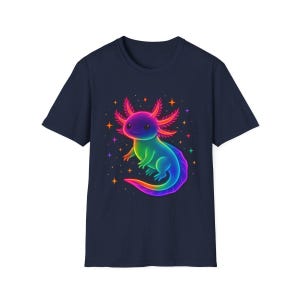 May include: A navy blue t-shirt with a colourful illustration of an axolotl. The axolotl is rendered in rainbow colours, smiling, and surrounded by stars. The design is printed on a classic crew neck tee.