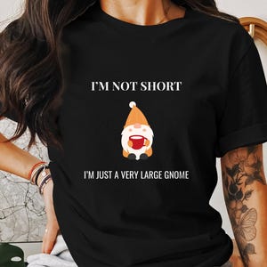 May include: Black t-shirt with white text that reads "I'm not short, I'm just a very large gnome." A cartoon gnome with an orange hat and beard is holding a red mug.