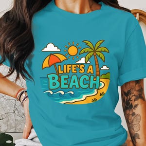 Maglietta Life's A Beach - Divertente maglietta con scena di spiaggia a cartoni animati, maglietta grafica estiva, abbigliamento con vibrazioni da vacanza, maglietta da spiaggia