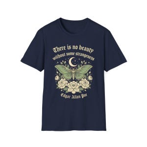 May include: Navy blue t-shirt featuring a green moth design with a crescent moon and floral accents. The shirt includes the quote "There is no beauty without some strangeness" and the name "Edgar Allan Poe".
