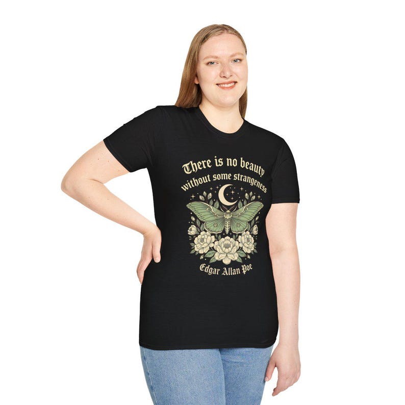 May include: Black t-shirt featuring a green moth design with a crescent moon and floral accents. The text "There is no beauty without some strangeness" and "Edgar Allan Poe" are printed on the shirt.