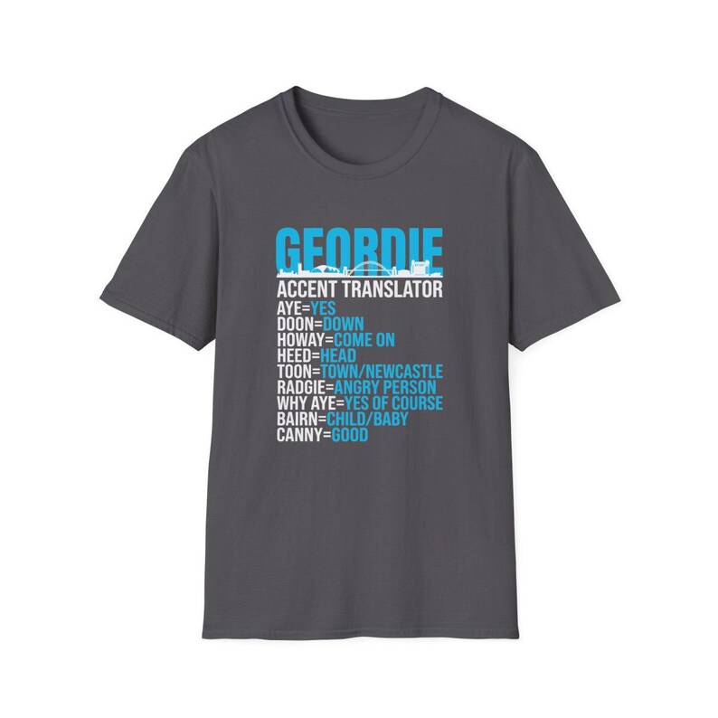 Puede incluir: Camiseta gris oscuro con la palabra "GEORDIE" en azul, sobre un traductor de acento. El traductor incluye frases como "AYE=YES" y "CANNY=GOOD". La camiseta tiene cuello redondo y mangas cortas.
