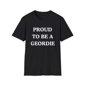 May include: A black short-sleeved t-shirt featuring the white text PROUD TO BE A GEORDIE centered on the chest. The garment has a crew neckline and a standard fit, constructed from a solid black fabric with bold, capitalized white lettering.