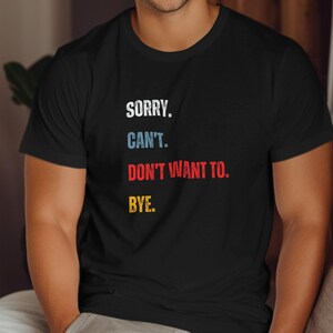 Può includere: Maglietta nera con il testo "SORRY. CAN'T. DON'T WANT TO. BYE." in lettere colorate.