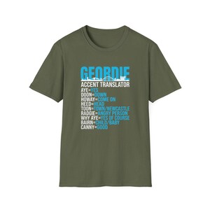 Puede incluir: Camiseta verde oliva con la palabra "GEORDIE" en letras azules en bloque y un traductor de acento debajo. El traductor incluye frases como "AYE=YES" y "CANNY=GOOD". La camiseta es de estilo casual.