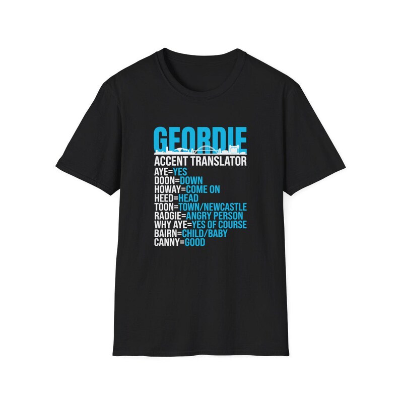 Puede incluir: Camiseta negra con la palabra "GEORDIE" en azul, encima de "ACCENT TRANSLATOR" y una lista de t&eacute;rminos de jerga Geordie y sus significados. Tambi&eacute;n hay una silueta del horizonte de la ciudad.