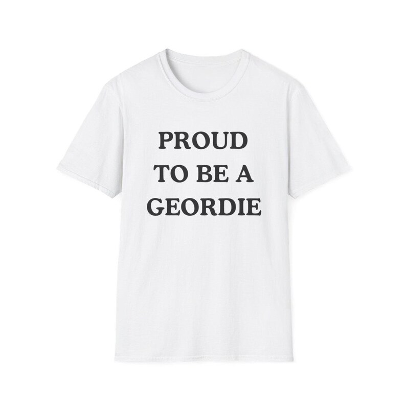 May include: A white short-sleeved t-shirt featuring the black text PROUD TO BE A GEORDIE centered on the chest. The garment has a classic crew neckline and a straight hemline, constructed from a plain white fabric with a simple, clean design.