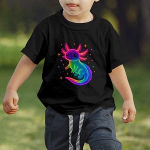 May include: Black t-shirt with a rainbow-coloured axolotl design. The axolotl is surrounded by stars. The t-shirt is worn by a child.