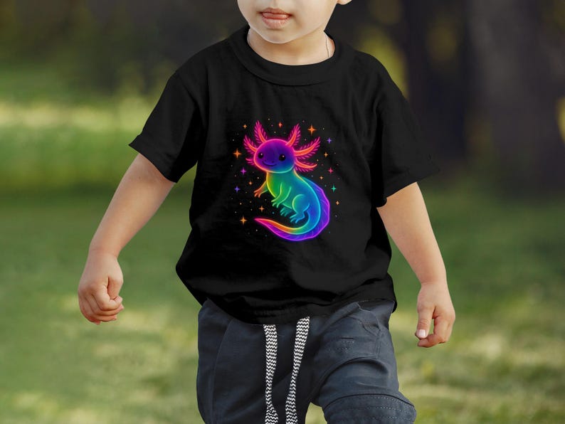 May include: Black t-shirt with a rainbow-coloured axolotl design. The axolotl is surrounded by stars. The t-shirt is worn by a child.