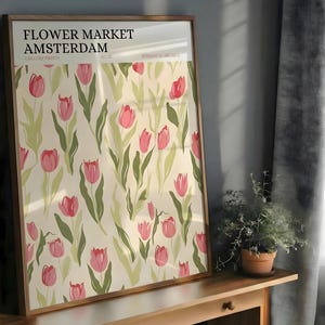 Large framed pastel botanical Amsterdam tulip pattern poster resting on a wooden cabinet near a dark grey curtain.