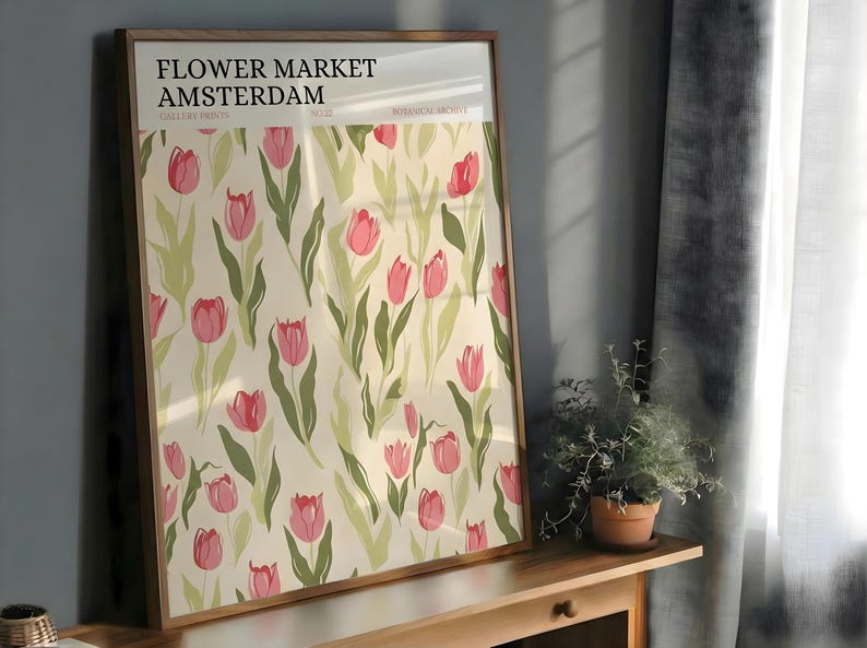 Large framed pastel botanical Amsterdam tulip pattern poster resting on a wooden cabinet near a dark grey curtain.