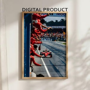Puede incluir: Una impresión digital enmarcada que muestra un coche de carreras de Fórmula 1 rojo pasando por un muro de boxes donde miembros del equipo con uniformes rojos se inclinan para celebrar. El texto DIGITAL PRODUCT aparece sobre el marco.