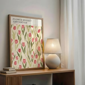 Cozy room corner with a wooden side table, a warm lamp, and a retro Amsterdam flower market print leaning against the wall.