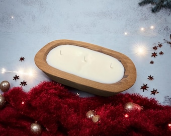 May include: A large, wooden, oval-shaped candle holder filled with white wax and three wicks. The candle holder sits on a red, fluffy surface, with gold ornaments and star-shaped decorations scattered around. The background is a light blue.