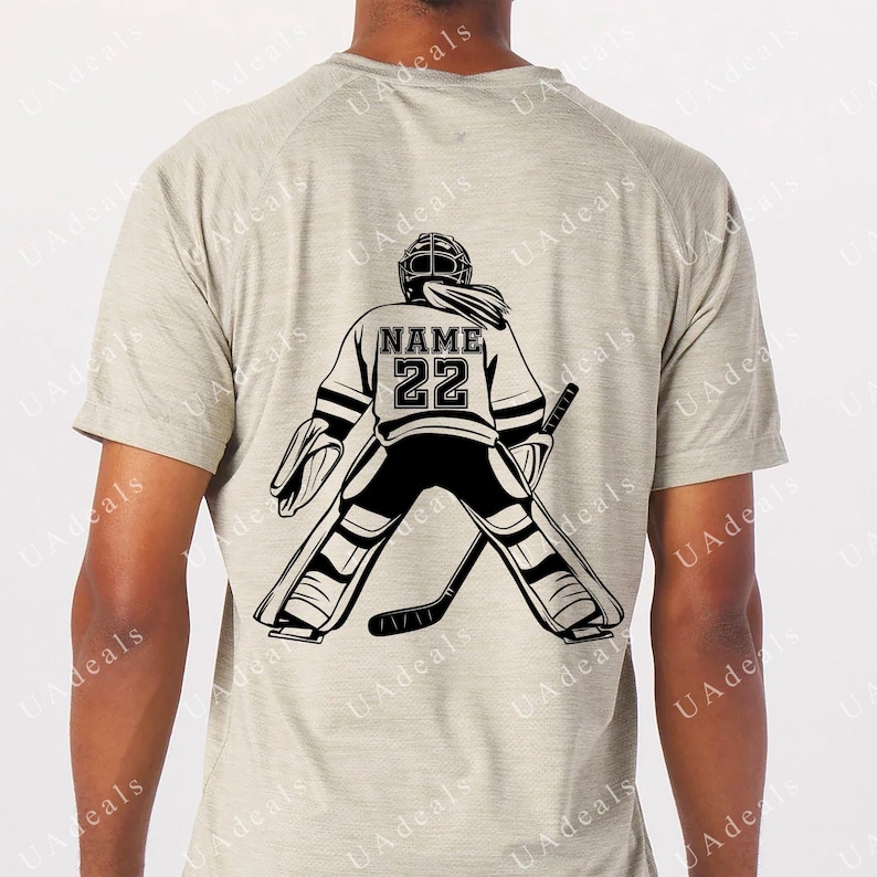 A digital graphic of a female hockey goalie seen from behind, wearing a jersey with the placeholder 'NAME' and the number '22'. The design is in black on a light gray shirt, showcasing the goalie stance with a stick.