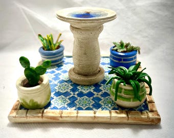 Patio en miniatura con plantas, macetas y bebedero para pájaros