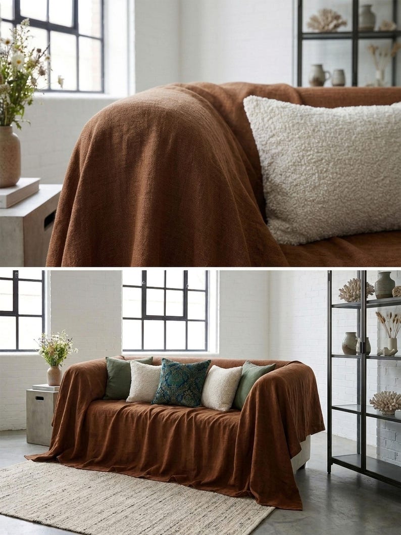 May include: A brown sofa draped with a matching throw blanket. Several decorative pillows in shades of green, white, and patterned blue are arranged on the sofa. A neutral rug and a black metal shelf unit are also visible.