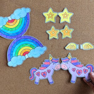 May include: Paper cutouts of rainbows, stars, wings, and unicorns. The unicorns are purple with pink manes and heart details. The stars are yellow with orange outlines. The rainbows have blue clouds.