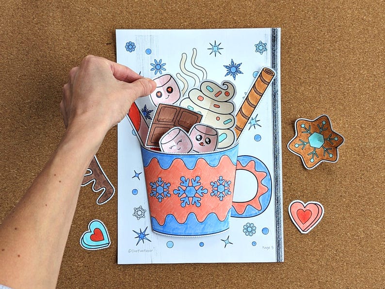 Peut inclure: Illustration color&eacute;e d'une tasse de chocolat chaud avec des guimauves, de la cr&egrave;me fouett&eacute;e et une gaufrette. La tasse est d&eacute;cor&eacute;e de flocons de neige et d'un motif bleu et orange. Formes d&eacute;coup&eacute;es suppl&eacute;mentaires : &eacute;toile en pain d'&eacute;pices et c&oelig;ur.