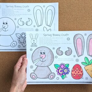 May include: Two sheets of paper with a "Spring Bunny Craft" design. The design includes a bunny, bunny ears, thumbs up, flowers, an egg, and a carrot. The bunny is gray with a pink nose. The text on the paper includes instructions.