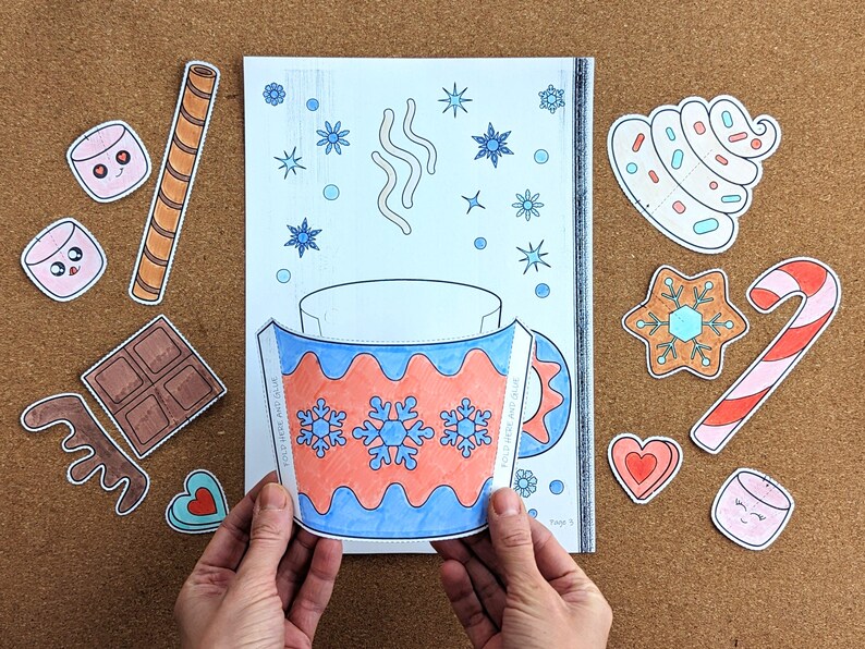 Peut inclure: Une page &agrave; colorier avec un motif de tasse, avec des flocons de neige et le texte "WINTER WARM UP". Autour de la tasse se trouvent des illustrations d&eacute;coup&eacute;es de guimauves, d'une barre chocolat&eacute;e, d'un biscuit, d'un sucre d'orge et d'autres &eacute;l&eacute;ments sur le th&egrave;me de l'hiver.