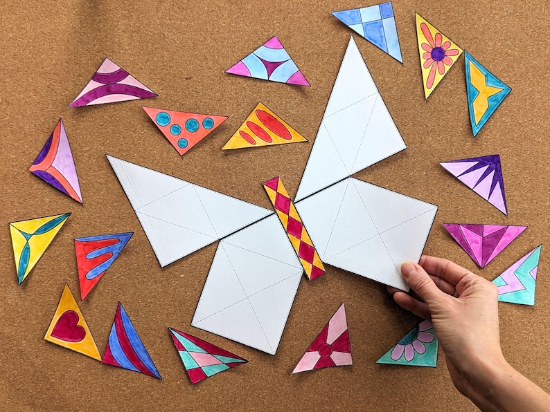 May include: A butterfly-shaped puzzle with white wings and a colorful body. Scattered around are various colorful triangle puzzle pieces with different patterns and designs. The puzzle is on a brown surface.
