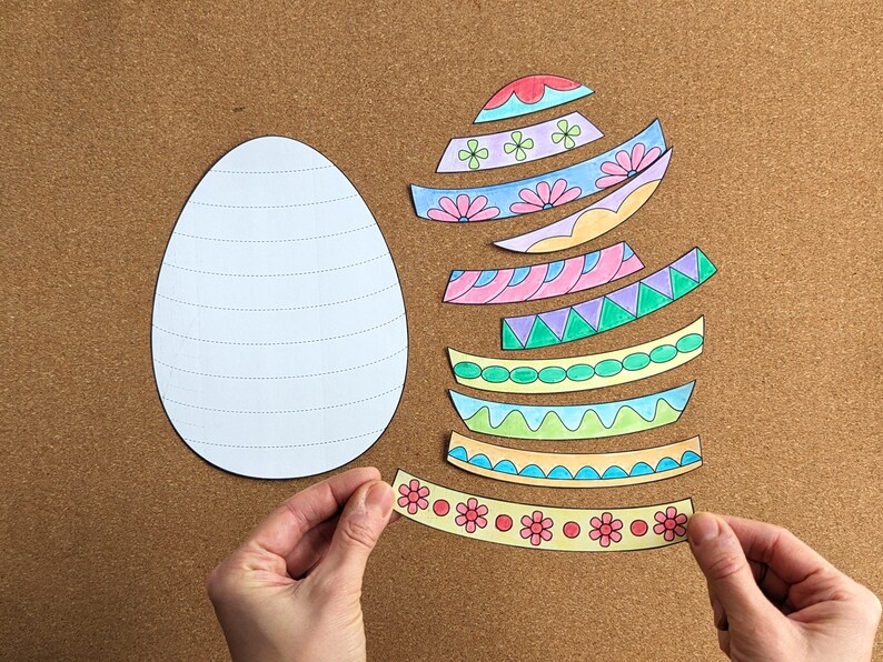 Pode incluir: Um projeto de artesanato com um contorno de ovo branco e tiras de papel coloridas e estampadas. As tiras t&ecirc;m desenhos florais e geom&eacute;tricos em v&aacute;rias cores, sugerindo um tema de P&aacute;scoa ou primavera.
