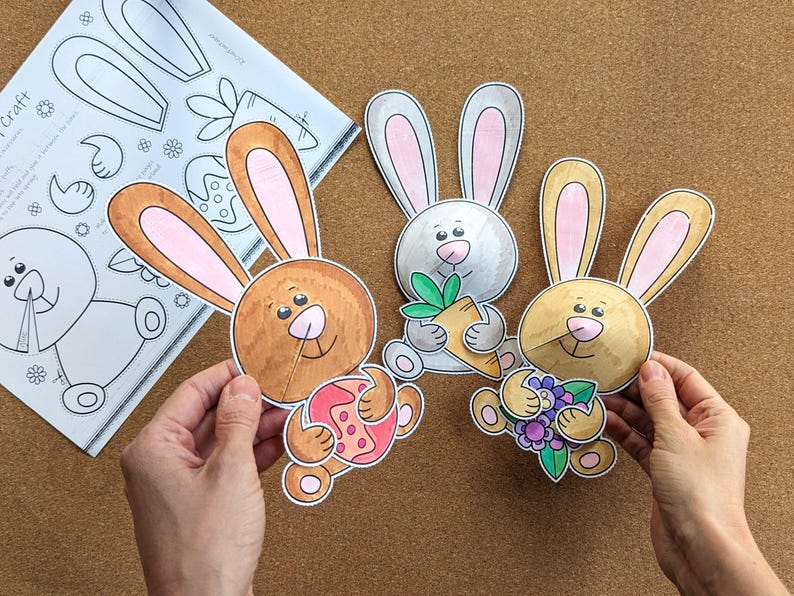 May include: Three colorful, cartoon bunny cutouts with pink-lined ears and smiling faces. One holds a carrot, another an Easter egg, and the third a bouquet of flowers. A sheet of bunny craft templates is in the background.