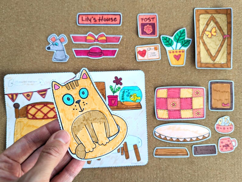May include: A collection of colorful, hand-drawn paper cutouts, including a cat, mouse, and various house-themed elements. The cat has blue eyes and is the central focus. Other items include a door, bed, and a fishbowl.