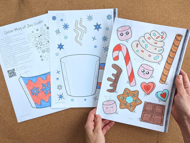 Peut inclure: Trois feuilles de papier avec un projet d'artisanat sur le th&egrave;me de l'hiver. La premi&egrave;re feuille contient des instructions et un code QR. La deuxi&egrave;me feuille a un contour de tasse et des flocons de neige. La troisi&egrave;me feuille a des images d&eacute;coup&eacute;es de bonbons, de guimauves et de biscuits en pain d'&eacute;pices.