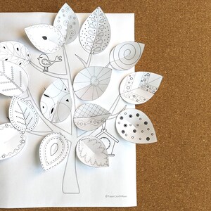 May include: A black and white printable paper craft tree with a bird and a birdhouse. The tree has leaves with different patterns and designs.