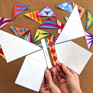 May include: A craft project featuring a butterfly design made from white paper and colorful triangle cutouts. The butterfly's wings are assembled from large white paper pieces with dotted lines. The triangles are decorated with various patterns and colors.