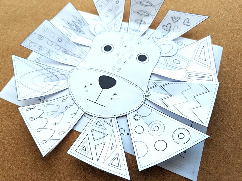 May include: A white paper lion craft with a black nose, eyes, and whiskers. The lion's mane is made of triangular and heart-shaped paper pieces, each decorated with geometric patterns. A fun DIY craft project.