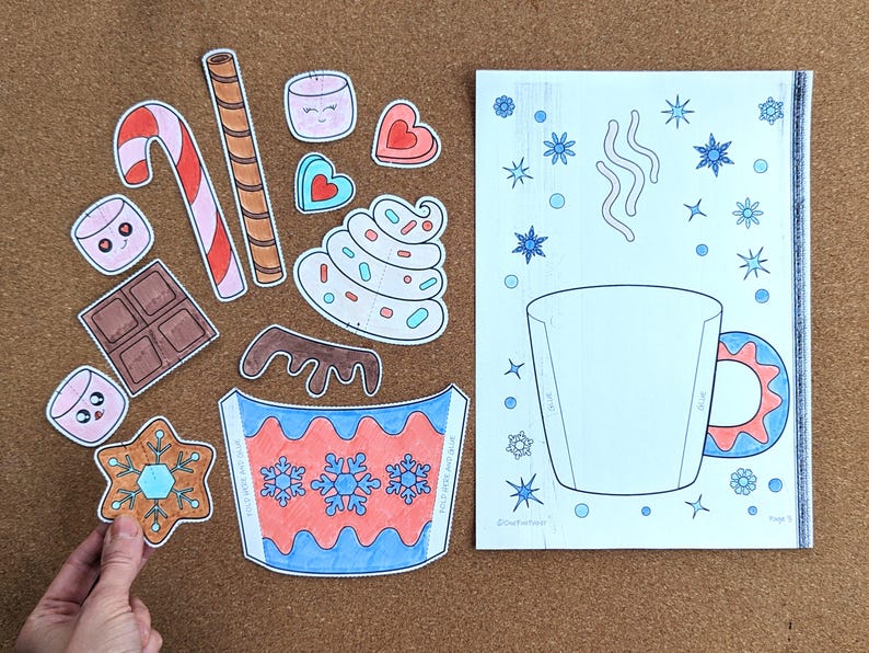 Peut inclure: Un ensemble de d&eacute;coupes en papier et une page &agrave; colorier sur le th&egrave;me de l'hiver. Les d&eacute;coupes comprennent une canne en bonbon, des guimauves, du chocolat et une tasse avec des flocons de neige. La page &agrave; colorier montre une tasse avec des flocons de neige et de la vapeur.