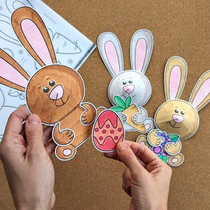 May include: A collection of Easter-themed paper cutouts featuring cartoon bunnies and an Easter egg. The bunnies are in various colors, including brown, white, and tan, with pink inner ears. One bunny holds an egg, another a carrot, and another a bunch of flowers.