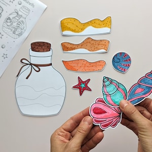 May include: A collection of colorful, hand-drawn seashell cutouts, including a large, detailed conch shell in shades of pink, blue, and green. Also present are a starfish, and several sand-colored wave shapes. A bottle outline and a sheet with the word "seashells" are also visible.