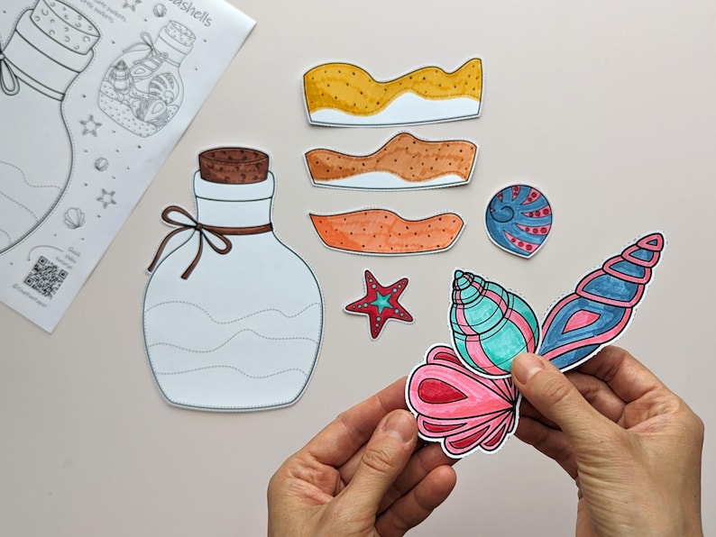 May include: A collection of colorful, hand-drawn seashell cutouts, including a large, detailed conch shell in shades of pink, blue, and green. Also present are a starfish, and several sand-colored wave shapes. A bottle outline and a sheet with the word "seashells" are also visible.