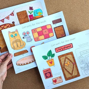 May include: Three sheets of paper with colorful, hand-drawn cut-out illustrations for a child's craft project. The sheets include images of a cat, mouse, bed, door, and other decorative elements. Text includes "Cut-outs for the inside" and "Lily's House".