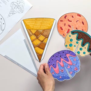 Op de afbeelding: Een verzameling kleurrijke, handgetekende ijsjes en bolletjes. De hoorn is geel en bruin, terwijl de bollen oranje, bruin en paars zijn met decoratieve details. Er zijn ook gedrukte sjablonen met ijsontwerpen.