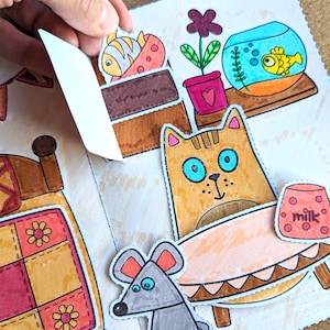 May include: A colorful, illustrated pop-up book with a cat, mouse, and fish. The cat has blue eyes and is near a table with a mug that says "milk." A fishbowl and a bed are also visible.