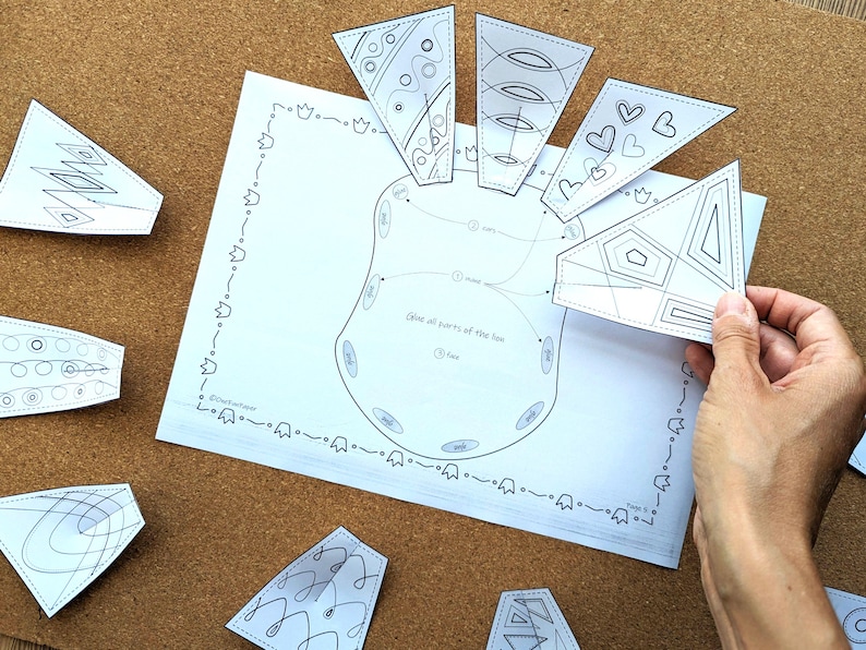 May include: A white paper with a diagram of a foot, surrounded by several white, geometric cutouts with black line art. The text "Glue all parts of the foot" is visible. The cutouts are being held by a hand.