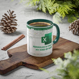 May include: A white ceramic mug with a green handle and rim, featuring a Microsoft Excel spreadsheet design. The mug has the text "FORMULAS & CHILL, MY KIND OF NIGHT" and a green Excel logo. The mug is filled with a hot beverage.