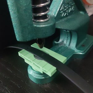 May include: A green metal press with a black spring and a green plastic guide with the text "Biothane® 15mm - 5/8" printed on it.
