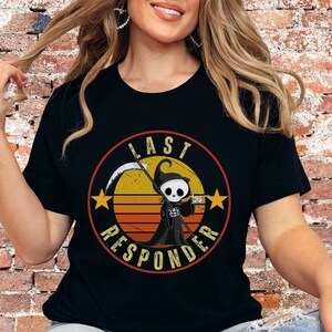 May include: Black t-shirt with a retro-style graphic of a cartoon Grim Reaper holding a scythe and a beer mug. The graphic is surrounded by a circle with the text "Last Responder" in white.