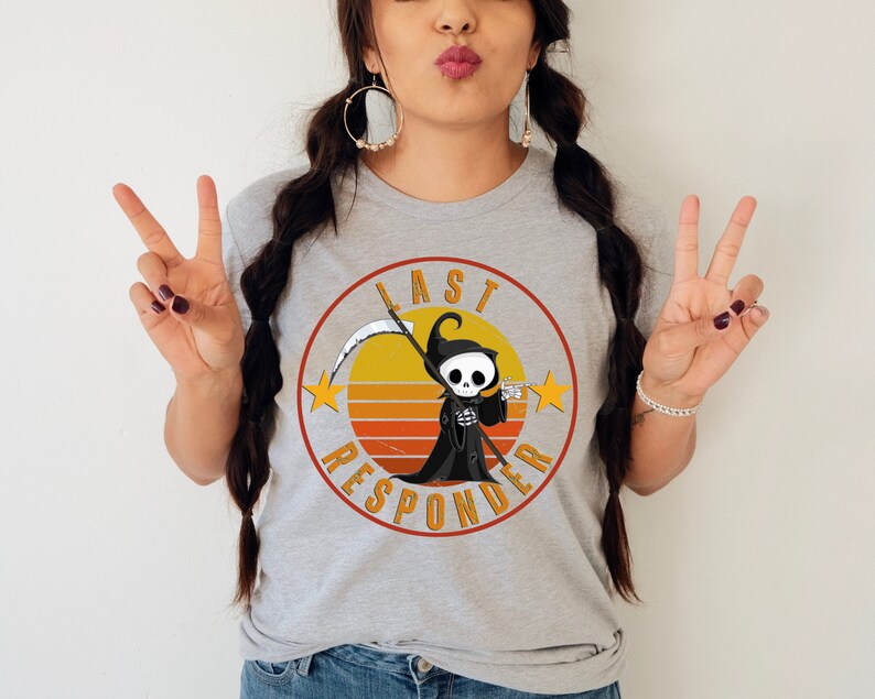 May include: A gray t-shirt with a retro-style graphic of a cartoon Grim Reaper holding a scythe. The graphic is surrounded by a circle with the text "Last Responder" in a vintage font.