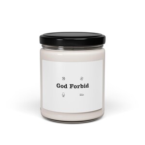 May include: A white candle in a glass jar with a black lid. The label features the text "God Forbid" with small icons of a book, chair, paper, and a document.