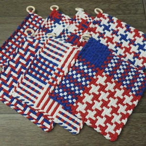 May include: Set of six red, white and blue woven pot holders with wooden rings. The pot holders feature different geometric patterns.
